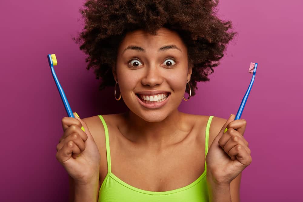 girl with an expression holding tooth brushes