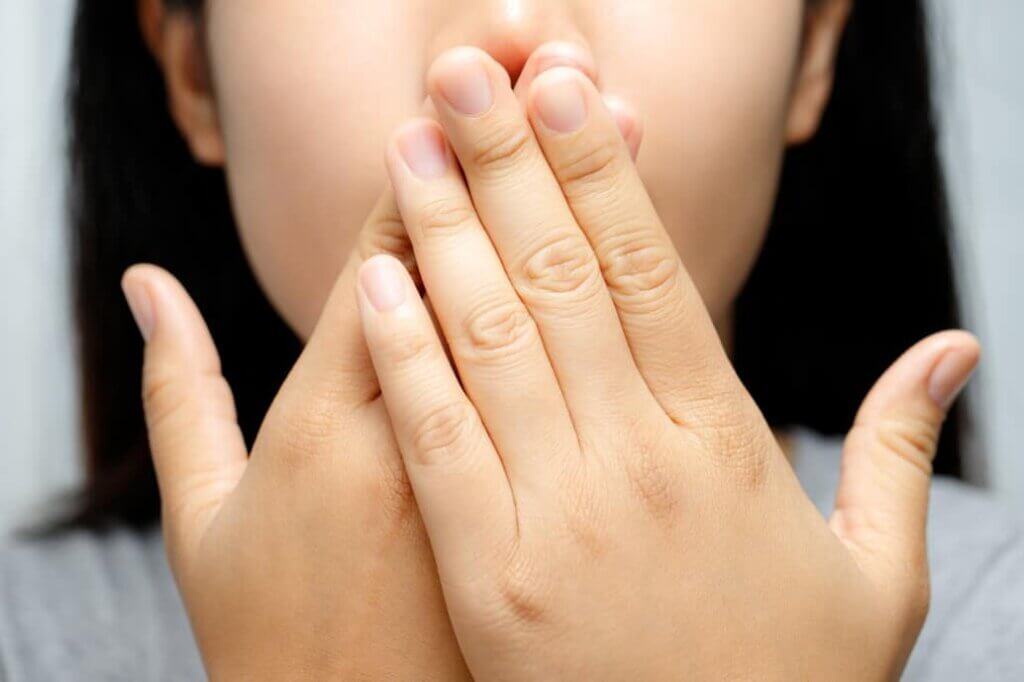 woman covering her mouth with two hands