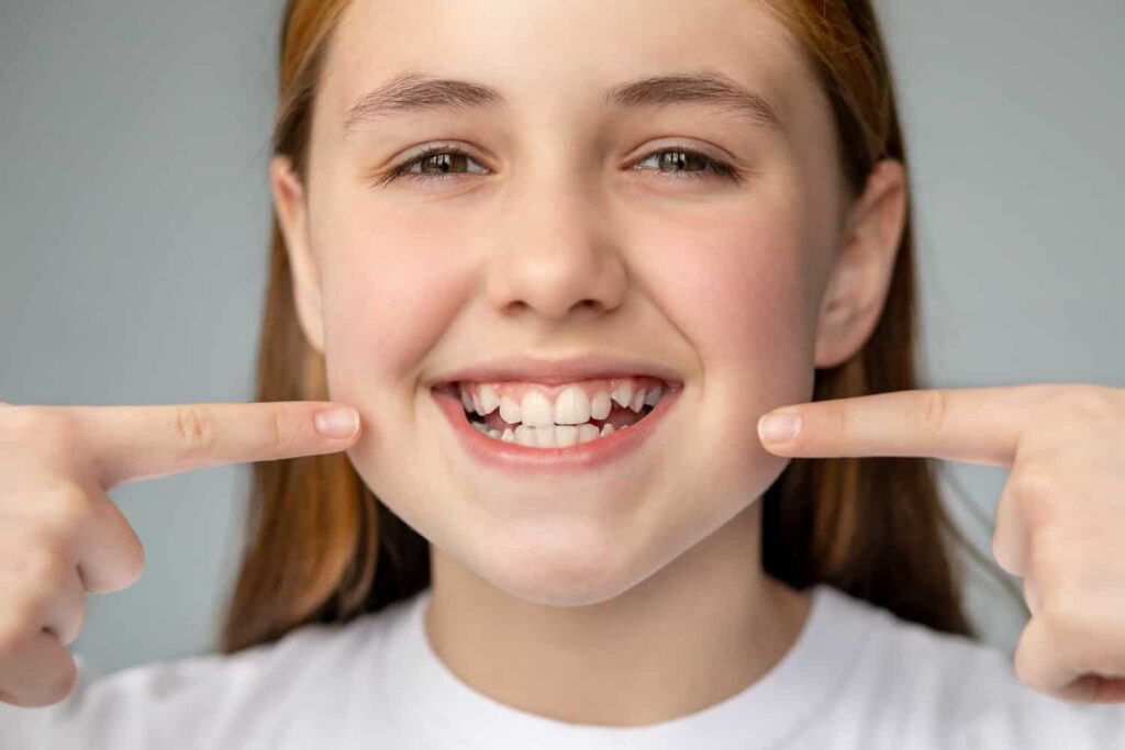 girl smiling with her uneven teeth
